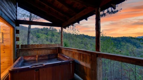 Covered cabin deck with a private hot tub, timber beams, and wide open views of the forested hills. (Jack's Cabin)