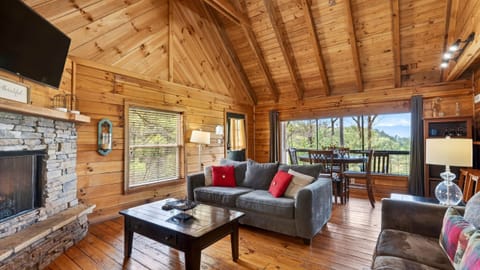Cozy up by the stone fireplace in this warm, wood-lined living space—perfect for relaxing evenings after a day in the mountains. (Elijah's Cabin)