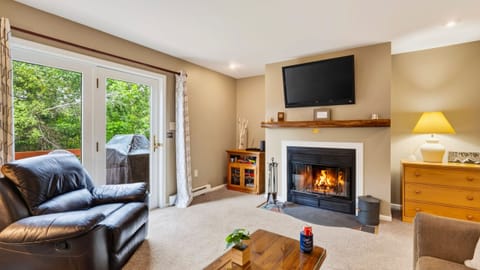 Living room featuring a stone fireplace, wall-mounted TV, and cozy seating area.