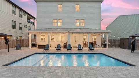 Resort-style backyard with private pool, covered game lounge, hot tub, and sunset skies.