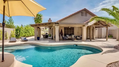 Private backyard pool with shaded lounge seating, covered outdoor living space, and a sunny desert feel.