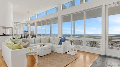 Wall-to-wall windows bring sweeping Gulf views into the bright living room, with plush sectional seating and direct access to the beachfront balcony.