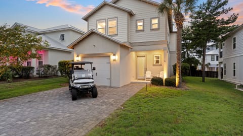 A welcoming twilight exterior with warm lights, a spacious drive, and an inviting coastal atmosphere.