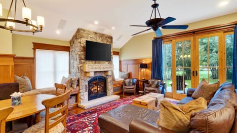 Warm, inviting living room with a stone fireplace, TV, and leafy views for cozy Park City evenings.