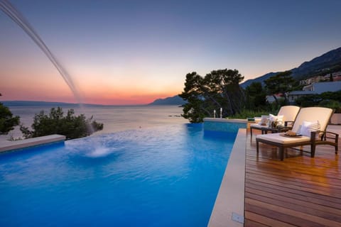 Property building, Patio, Nearby landmark, Day, Natural landscape, Summer, Balcony/Terrace, Balcony/Terrace, Living room, Seating area, Beach, Mountain view, Pool view, Sea view, Swimming pool, Swimming pool, Sunset, sunbed