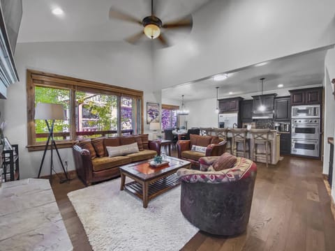 This cozy mountain lounge features a warm stone fireplace, plush seating, and vaulted ceilings. Relax with a movie or enjoy the natural light from large windows overlooking the trees.