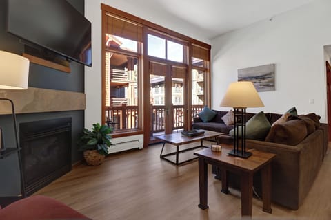 Unwind in your cozy mountain retreat with a crackling fireplace, plush seating, and stunning balcony views of the surrounding alpine architecture - your perfect home base for relaxation.