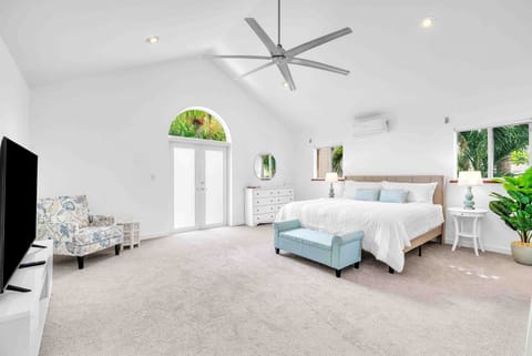 Roomy Master Bedroom, complete with a plush king-sized bed, a cozy reading couch, a thoughtfully positioned TV for added comfort, an a private balcony.