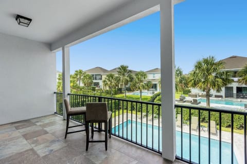 The patio features two stylish chairs with soft cushions, positioned to overlook a sparkling blue pool.
