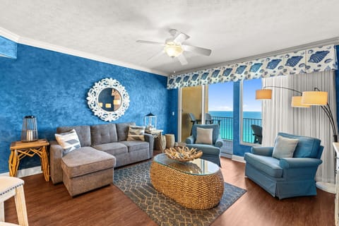 Relax in your coastal-themed living room with stunning ocean views through floor-to-ceiling windows, complete with comfortable seating and beach-inspired décor.