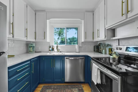 Cook your favorite meals in this bright, modern kitchen featuring elegant two-tone cabinetry and sleek stainless steel appliances.