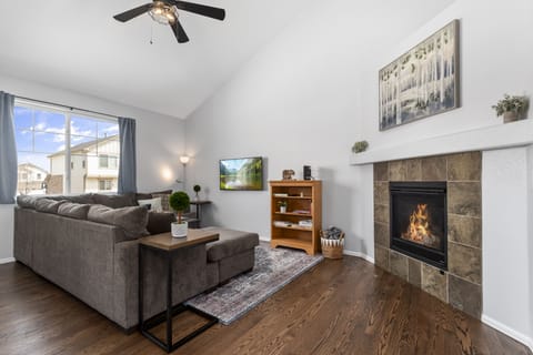 Vaulted ceiling living room with a gas fireplace, TV, books, and games