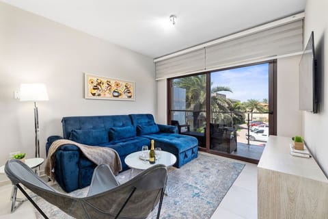 Modern living room with plush blue sofa, stylish decor, large windows, and balcony views.