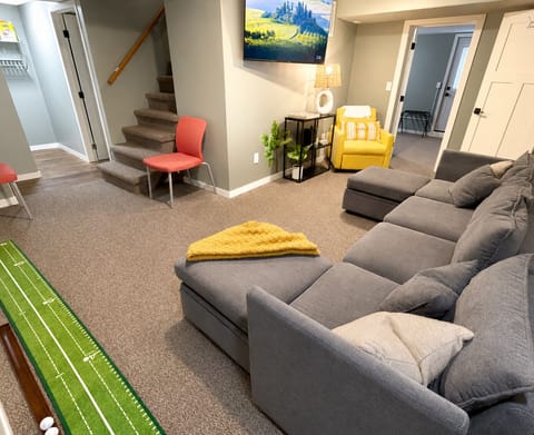 Living room featuring 55” big screen TV, indoor golf, pull out couch & sofa bed