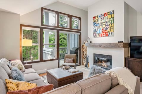 Living Room: A spacious and comfortable seating arrangement with large windows. Equipped with a wood burning fireplace and  Smart TV with Apple TV and more.