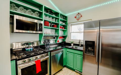 A green and black kitchen fully equipped with complete utensils, blending modern design with practicality for culinary excellence.