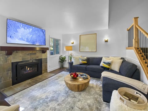 Unwind in this inviting living space featuring a sleek gas fireplace, large smart TV, and plush sectional seating. A bright and airy sanctuary designed for ultimate comfort and relaxation.