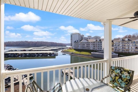 The covered private balcony offers a table and chairs overlooking the resort buildings, lake, and marina.
