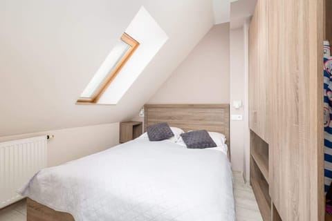 A cozy attic bedroom with a sloped ceiling, a large bed, and wooden wardrobes.

