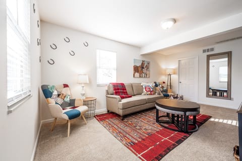 Living room with cozy couch set and mirror and airy windows