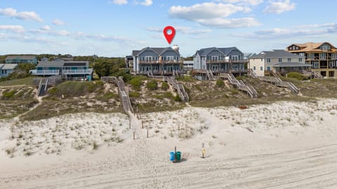 Beachfront vacation homes line pristine sandy shores with private access stairs leading directly to the beach below.