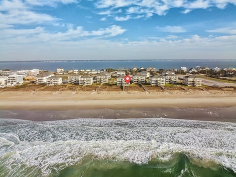 Aerial view showcasing beachfront vacation rental properties with direct access to pristine sandy shores and rolling ocean waves.