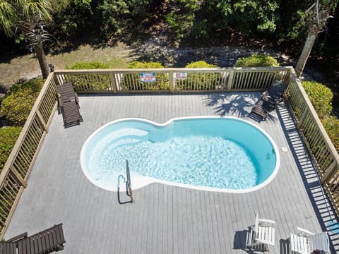 Aerial view of the private pool deck featuring a kidney-shaped pool surrounded by wooden decking and tropical landscaping.