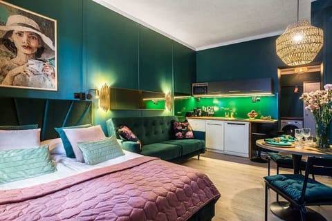 A stylish bedroom with teal walls, a pink quilt, and gold accents.

