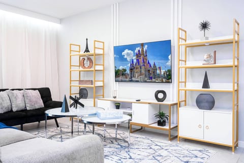 Enjoy a stylish living room featuring plush gray sofas and a chic coffee table, perfect for relaxation. Unique shelving showcases modern decor, while bright walls and natural light create an uplifting atmosphere for your stay.