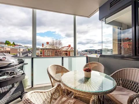 Step onto the large covered balcony, furnished with a four-seat outdoor table setting and a BBQ grill. 