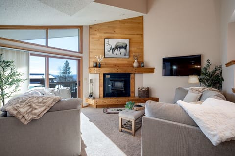 Sink into plush sofas by your cozy fireplace while mountain views frame your perfect alpine getaway through expansive windows.