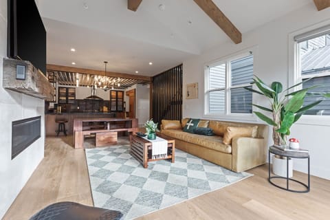 Unwind in your open-concept living space where natural wood beams and modern design blend beautifully, creating a warm retreat for relaxation and connection.