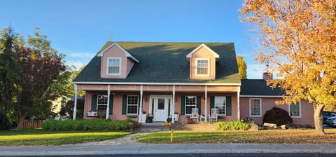 Beautiful mauve-creek farmhouse cottage with green tiled roof and peaked alcove.