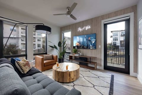 Bright open living space featuring a smart flat-screen TV, designer furnishings, and access to the private patio.