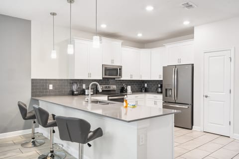 Modern kitchen with white cabinets, gray backsplash, island.