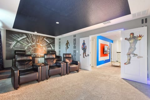 Stylish home theater with recliners, superhero décor, and starry theme.
