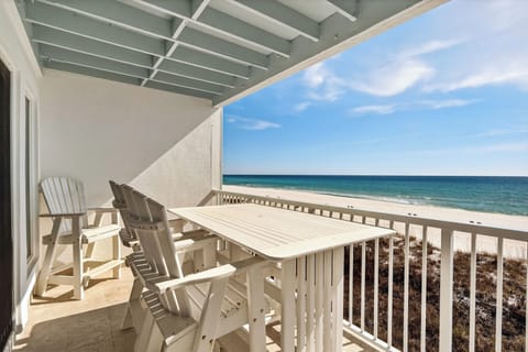 Covered balcony with white outdoor dining table and an ocean view.