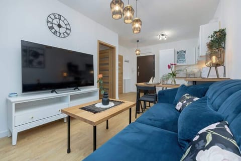 A living room with a blue sectional sofa, coffee table, and wall-mounted TV.
