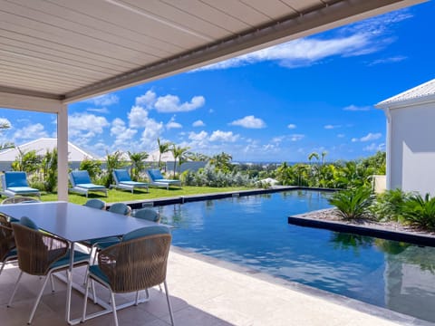 Elegant villa with covered terrace, infinity pool, and loungers, offering breathtaking sea views.