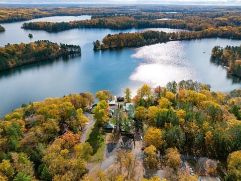 Aerial view of Moose Ridge at The Spot, featuring autumn-colored forests surrounding a calm lake under a bright sky.