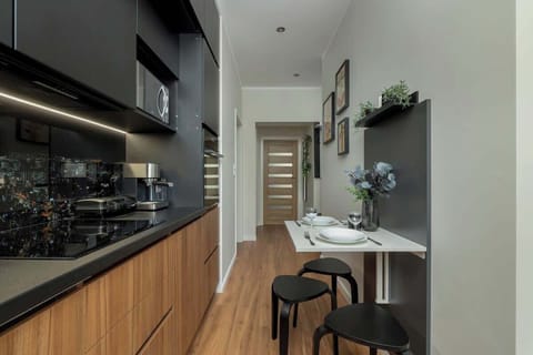 A view down the hallway connecting the kitchen and dining area with the rest of the apartment, featuring warm wood accents.