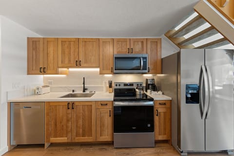 Your fully equipped kitchen features warm wood cabinetry and stainless steel appliances, perfect for preparing meals during your stay.