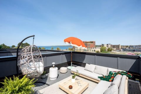 Private rooftop lounge w/ hanging chair & cushioned seating, perfect for sunset views over the city.