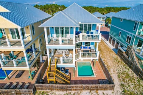 Aerial view of colorful beach houses featuring a private swimming pool and multiple balconies in a coastal rental community.