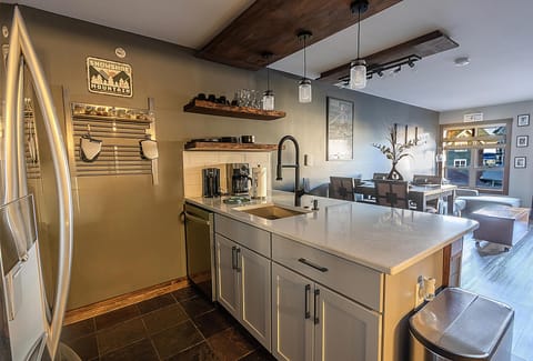 The modern kitchen has beautiful marble countertops and island with seating for four people.