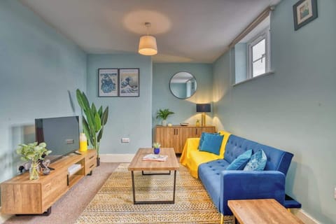 Relax in style in this serene blue-themed living room, featuring a plush sofa and a sleek smart TV-perfect for cozy nights and entertainment.