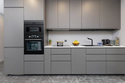 A sleek kitchen in matte grey, complete with built-in appliances, ample storage, and a minimalist design aesthetic.

