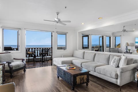 Relax in your bright living room where panoramic ocean views through floor-to-ceiling windows create the perfect coastal retreat atmosphere.