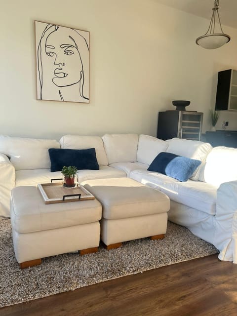 Welcome to Laid Back in Langford! Enjoy the living room with Langford sun, plush white sectional, and soft ottoman.
