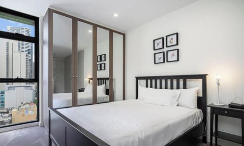 Bedroom featuring a queen-size bed, bedside tables, and balcony access.